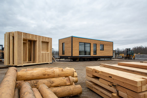 Modular cabin unit, panelized walls, and pre-cut log components in a construction yard